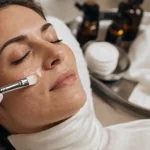 Soin peeling visage appliqué sur la joue, teint lumineux et texture de peau visible